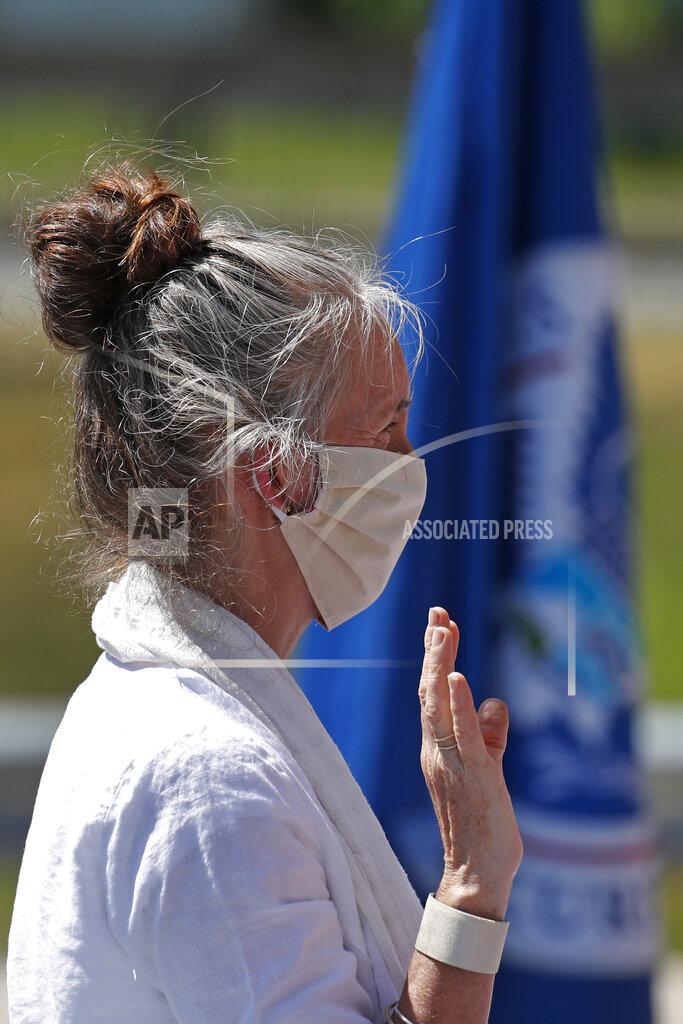 Tamara Sheen, originally from England, is sworn in as a new citizen outside the U.S. Citizenship and Immigration Services building, Thursday, June 4, 2020, in Lawrence, Mass. The federal agency is resuming services in many cities across the country after being shuttered for more than two months because of the coronavirus pandemic. (AP Photo/Elise Amendola)