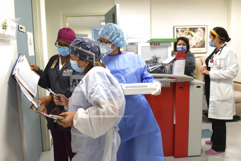 Taimy Alvarez Infectious diseases research assistant Irma Barreto Ojeda, right, holds a tray with a syringe containing either a placebo or the Moderna COVID-19 vaccine as she confers with University of Miami Miller School of Medicine nurse Inza Patton, left, and pharmacist Barbara Huang Wednesday, Sept. 2, 2020 in Miami, as part of the National Institutes of Health-funded third phase of a clinical trial. They go through a verification process to confirm the right study participant is receiving the correct injection of either a placebo or the vaccine, which is only known to the pharmacy team. (AP Photo/Taimy Alvarez)