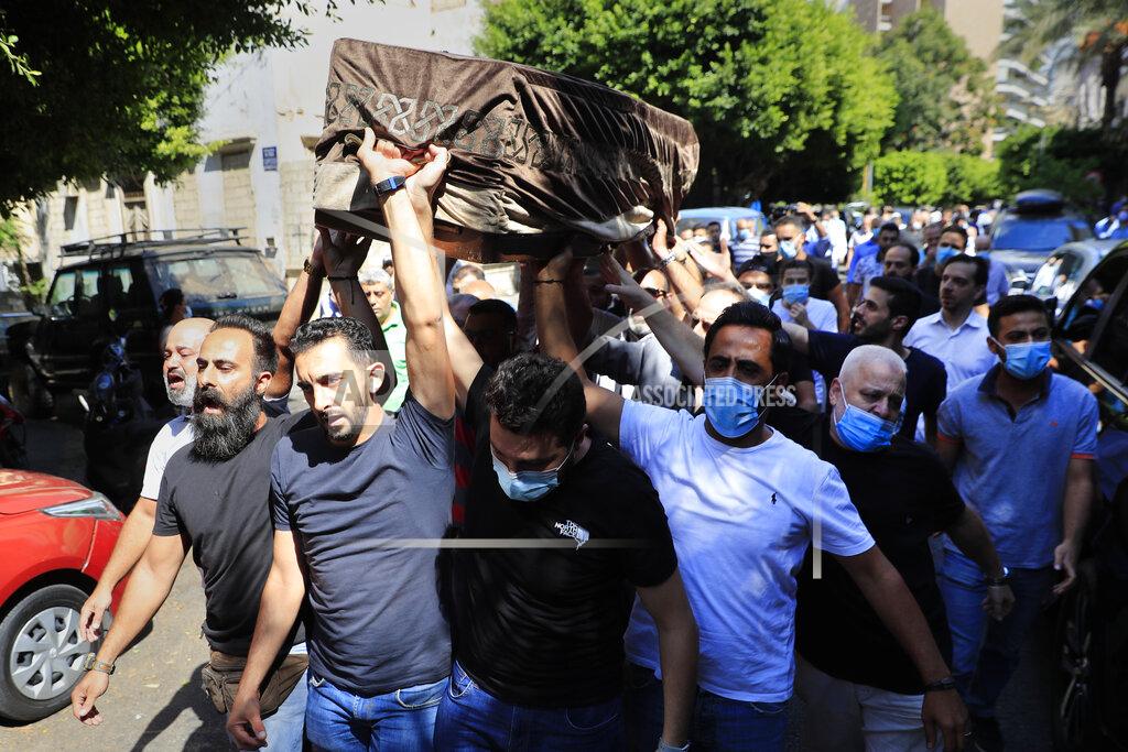 Hussein Malla Mourners carry the coffin of Ibrahim Harb, 35, who was critically injured in the massive explosion at Beirut's port last year and who died on Monday nearly 14 months after the blast, during his funeral procession, in Beirut, Lebanon, Tuesday, Sept. 28, 2021. On Aug. 4, 2020, hundreds of tons of ammonium nitrate, a highly explosive material used in fertilizers, ignited after a massive fire at the port. The death brings to at least 215 the number of people who have been killed by the blast, according to official records. (AP Photo/Hussein Malla)