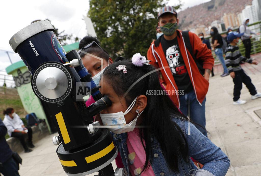 Juan Karita A girl looks at a partial solar eclipse through a telescope in La Paz, Bolivia, Monday, Dec. 14, 2020. The total solar eclipse was visible from the northern Patagonia region of Argentina and from Araucania in Chile, and as a partial eclipse from the lower two-thirds of South America. (AP Photo/Juan Karita)