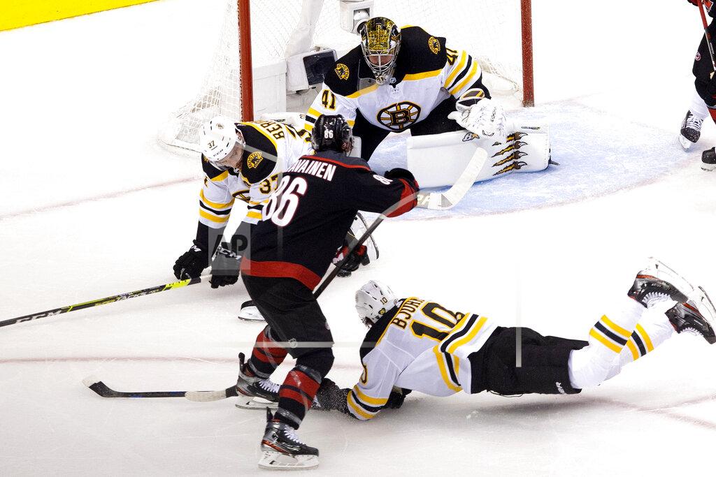 Chris Young Boston Bruins' Patrice Bergeron (37) and Anders Bjork (10) try to block a shot from Carolina Hurricanes' Teuvo Teravainen (86) as Bruins goaltender Jaroslav Halak (41) looks on during first period NHL Eastern Conference Stanley Cup playoff game in Toronto on Saturday, Aug. 15, 2020. (Chris Young/The Canadian Press via AP)