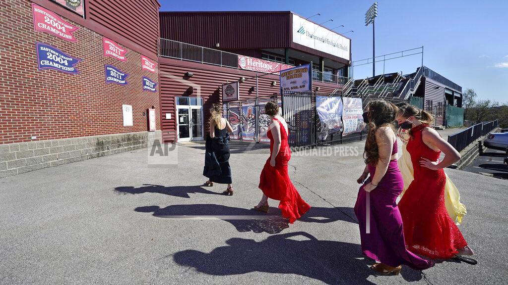 Charles Krupa While wearing their prom gowns, students walk towards the entrance at the New Hampshire Fisher Cats minor league baseball stadium in Manchester, N.H., on Monday, April 26, 2021. After a year without proms, school districts across the country are debating whether they can safely hold an event that many seniors consider a capstone to their high school experience. The nearly 300 student senior class of Manchester's Central High School are waiting to get approval from the city's board of health so they can have their prom at the outdoor venue, due to COVID-19 concerns. (AP Photo/Charles Krupa)