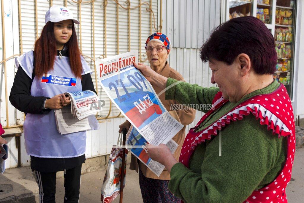 Uncredited A volunteer of Luhansk regional election commission distributes newspapers to local citizens prior to a referendum in Luhansk, Luhansk People's Republic controlled by Russia-backed separatists, eastern Ukraine, Thursday, Sept. 22, 2022. Authorities in Russian-controlled regions in eastern and southern Ukraine are preparing to hold referendums on becoming part of Russia — a move that could allow Moscow to escalate the war. The votes start Friday in the Luhansk, Kherson and partly Russian-controlled Zaporizhzhia and Donetsk regions. Writing on newspaper reads in Russian "27.09 Yes." (AP Photo)