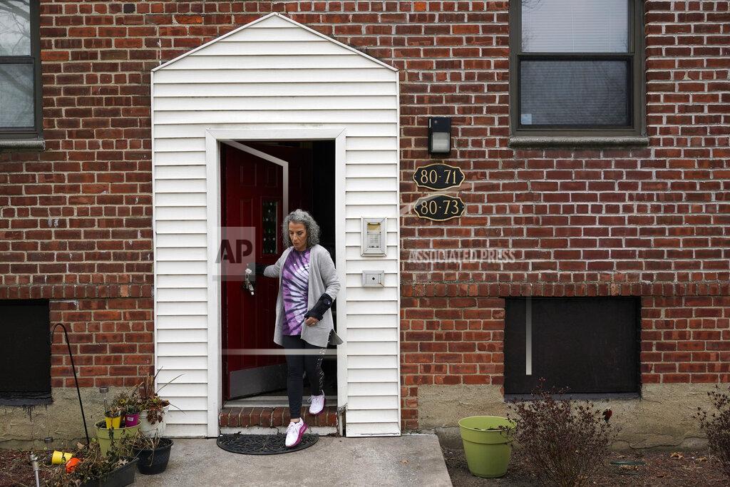 Seth Wenig Catherine Busa leaves her apartment for a walk as part of her recovery from COVID-19 in New York, Wednesday, Jan. 13, 2021. The 54-year-old New York City school secretary didn’t have any underlying health problems when she caught the coronavirus in March and recovered at her Queens home. But some symptoms lingered. After eights months of suffering, she made her way to Jamaica Hospital Medical Center — to a clinic specifically for post-COVID-19 care. (AP Photo/Seth Wenig)