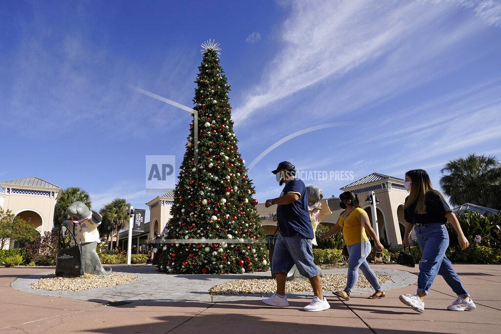 Chris O'meara Shoppers wear protective face masks as they walk past a Christmas setting at the Ellenton Premium Outlet stores Friday, Nov. 27, 2020, in Ellenton, Fla. Attendance at the mall was down in an attempt to avoid spreading the corona virus. (AP Photo/Chris O'Meara)