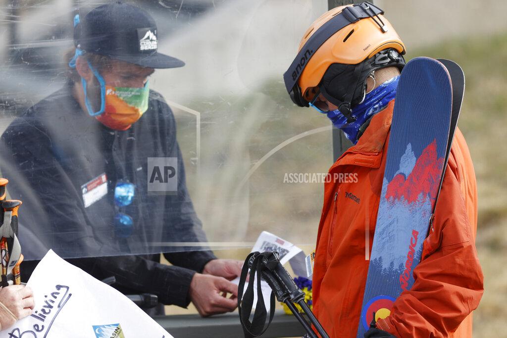 An employee is protected by a plexiglass shield while processing a skier at the reopening of Arapahoe Basin Ski Resort, which closed in mid-March to help in the effort to stop the spread of the new coronavirus, in a Wednesday, May 27, 2020 file photo, in Keystone, Colo. An executive order signed y President Donald Trump that temporarily bans a wide variety of foreign visas has thrown another obstacle in the path of ski resorts as they try to hire enough temporary workers to fill crucial jobs in the era of COVID-19. (AP Photo/David Zalubowski, File)