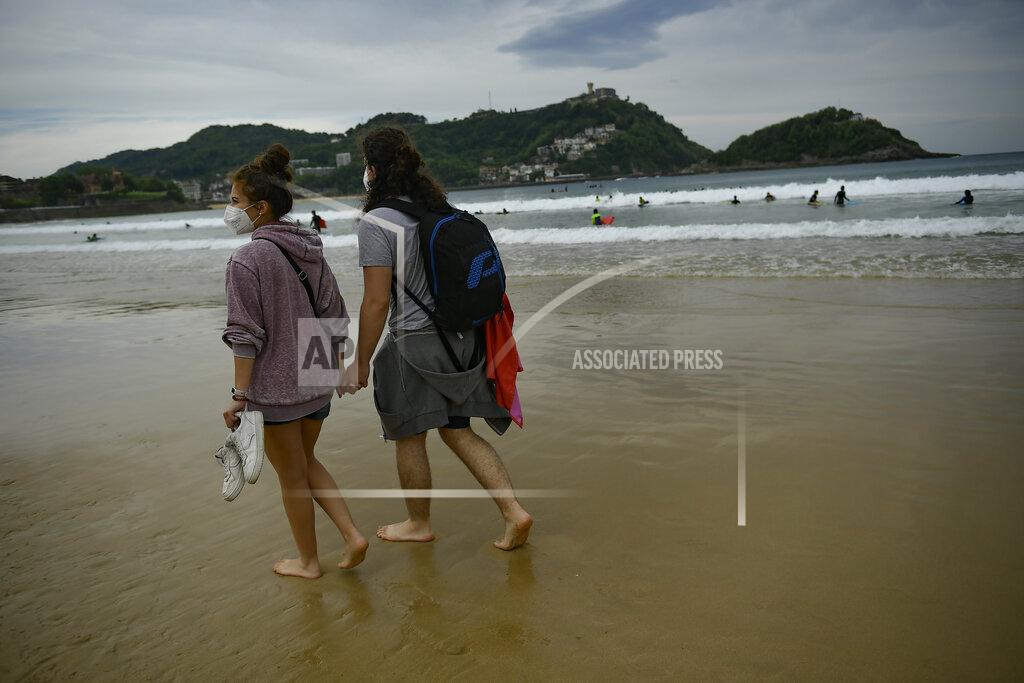 Alvaro Barrientos A couple walk along La Concha beach, after lockdown restrictions were lifted, in San Sebastian, northern Spain, Sunday, May 9, 2021. Impromptu street celebrations erupted across Spain as the clock struck midnight on Saturday, when a six-month-long national state of emergency to contain the spread of coronavirus ended and many nighttime curfews were lifted. (AP Photo/Alvaro Barrientos)