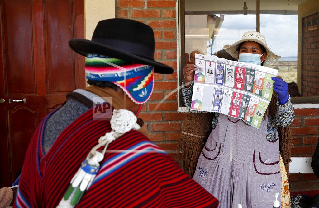 Juan Karita An electoral official shows the ballot to an Aymara man during general elections in Jesus de Machaca, Bolivia, Sunday, Oct. 18, 2020. (AP Photo/Juan Karita)