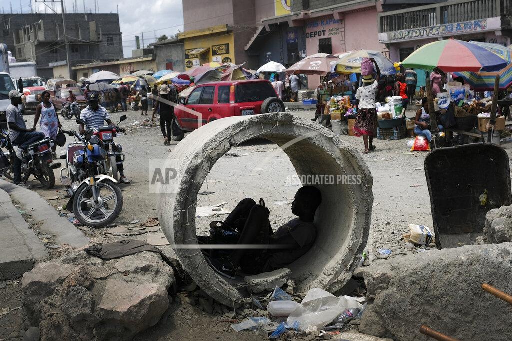 Matias Delacroix A man uses his cellphone inside a concrete pipe at a market in Cap-Haitien, Haiti, Thursday, July 22, 2021. The city of Cap-Haitien is holding events to honor slain President Jovenel Moïse on Thursday ahead of Friday’s funeral. (AP Photo/Matias Delacroix)