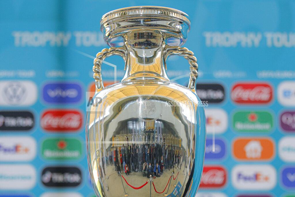 Vadim Ghirda FILE - In this Sunday, April 25, 2021 file photo, journalists are reflected in the Euro 2020 soccer tournament trophy at the National Arena stadium, a tournament venue, in Bucharest, Romania. UEFA set itself a challenge deciding nine years ago to let a dozen cities around Europe host its marquee European Championship in 2020. The multi-country project means more fans can see their own team in a stadium than if Euro 2020 was being traditionally hosted by a single nation amid international travel restrictions. (AP Photo/Vadim Ghirda, File)