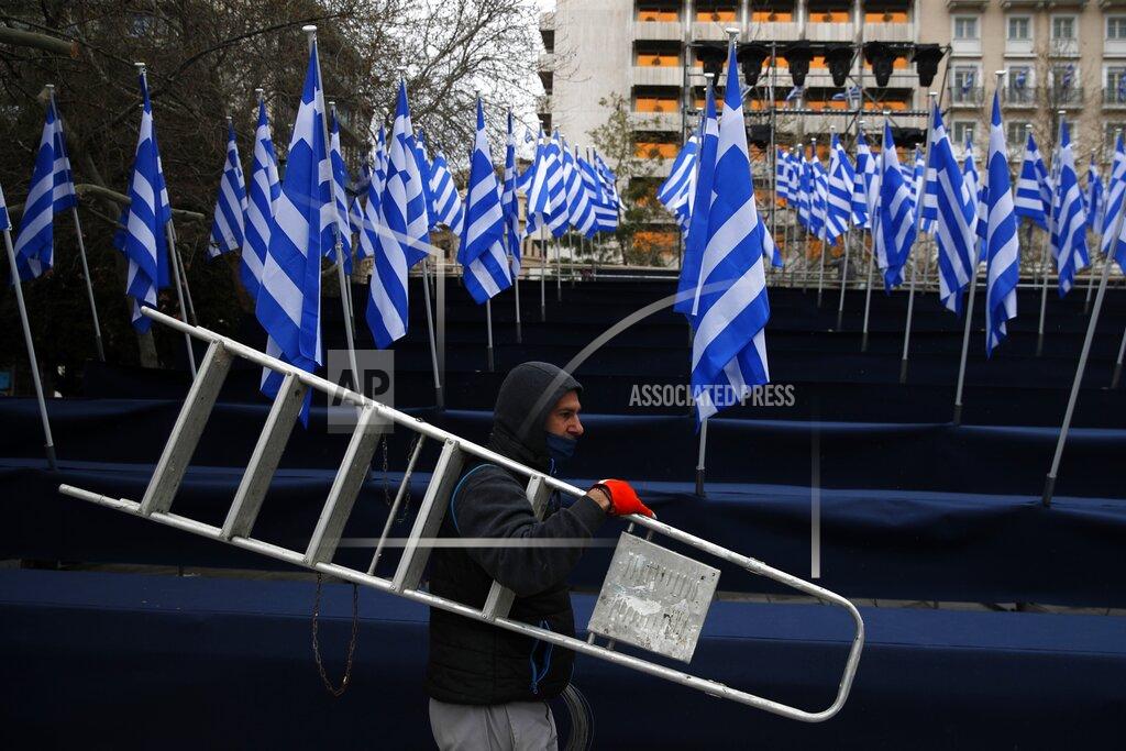 Thanassis Stavrakis A worker carrying a ladder, passes in front of tribune with Greek flags, ahead of a military parade, in Athens, Tuesday, March 23, 2021. The military parade on March 25, marking 200-years since the war that resulted in Greece's independence from the Ottoman Empire and rebirth as a nation, will be held without spectators due to the coronavirus. (AP Photo/Thanassis Stavrakis)