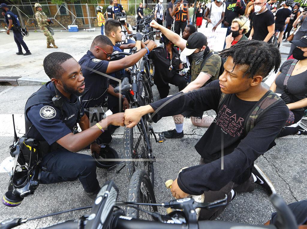 Curtis Compton FILE - Atlanta police officer J. Coleman, left, and protester Elijah Raffington fist bump while officers kneel down with protesters in a symbolic gesture of solidarity outside the CNN Center, Wednesday, June 3, 2020, in Atlanta during a protest sparked by the May 25 death of George Floyd in Minneapolis police custody. "These are images from Donald Trump's America today," Democratic presidential nominee Joe Biden said Thursday, Aug. 27, 2020. "The violence we're witnessing is happening under Donald Trump. Not me. It's getting worse, and we know why." (Curtis Compton/Atlanta Journal-Constitution via AP, File)