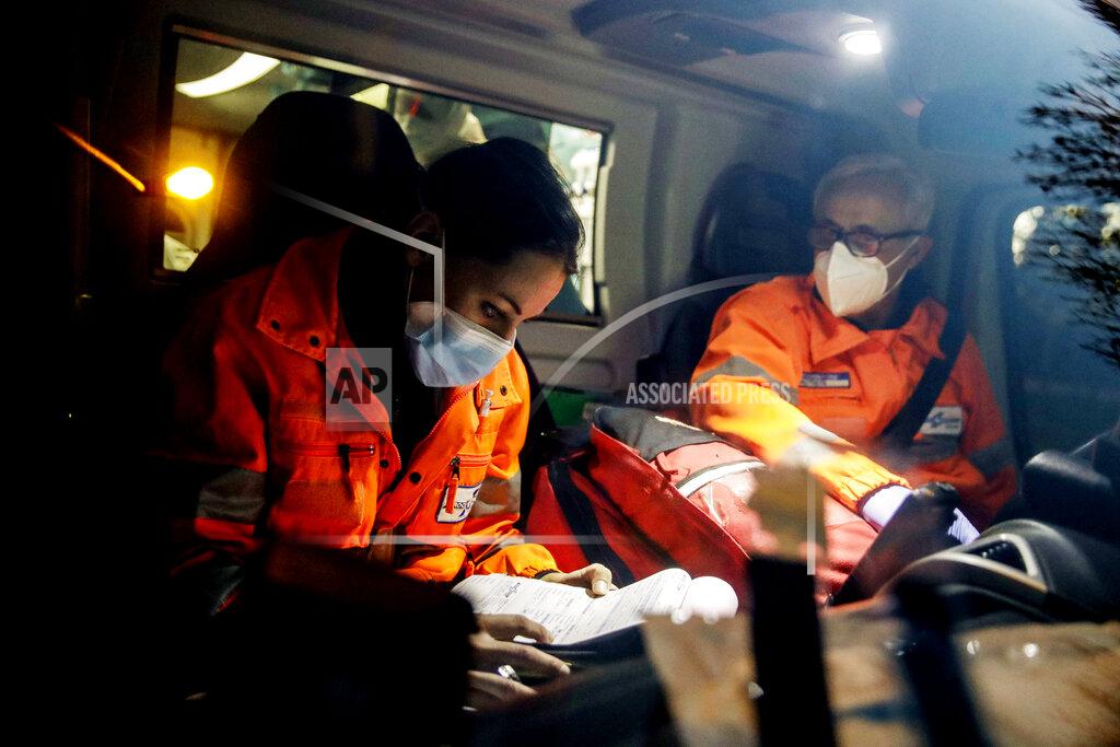 Luca Bruno Medical staffers Elisa Bonalumi and Massimo Villa work into the ambulance carrying a suspected Covid patient during their shift with the emergency White Cross in Monza, Italy, Friday, Nov. 20, 2020. The city of Monza north of Milan is best known for its Formula 1 racetrack. In 2020, it has been the ambulance service that has been doing most of the racing. Over three days that an Associated Press photographer traveled on night calls with an ambulance service, the Monza-Brianza province of some 875,000 bordering Milan added 2,500 new cases, part of Italy’s new epicenter in the Lombardy region. (AP Photo/Luca Bruno)