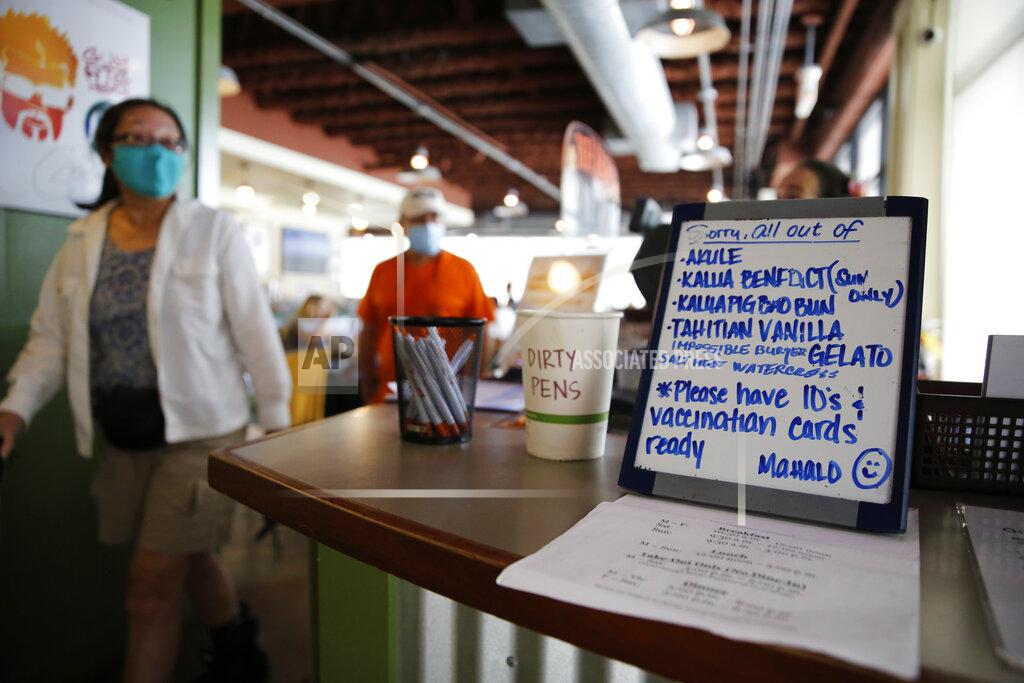 Caleb Jones Customers walk past a sign reminding people to have their vaccination cards ready at Highway Inn restaurant in Honolulu on Monday, Oct. 25, 2021. To comply with local mandates, the restaurant requires all indoor diners to show proof of vaccination or have a recent negative test result before being seated. (AP Photo/Caleb Jones)