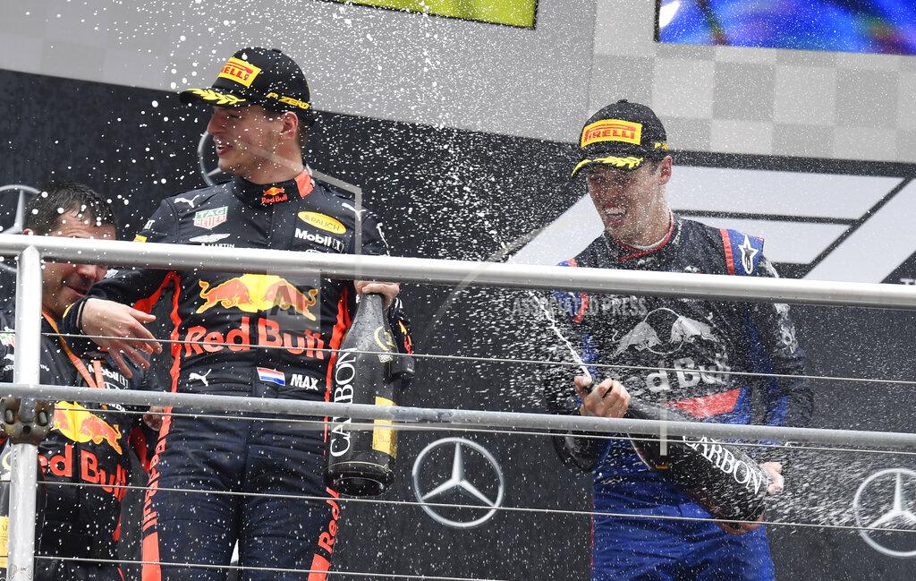 Jens Meyer Toro Rosso driver Daniil Kvyat of Russia sprays champagne to the winner Red Bull driver Max Verstappen of the Netherland's, on the podium after the German Formula One Grand Prix at the Hockenheimring racetrack in Hockenheim, Germany, Sunday, July 28, 2019. (AP Photo/Jens Meyer)