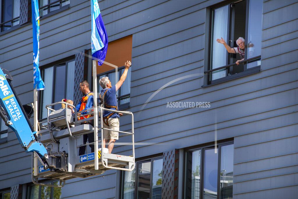 Peter Dejong Pitrik van der Lubbe waves from a crane to his 88-year-old father Henk, right, whom he has not seen in over 4 weeks at nursing home Hanepraij in Gouda, Netherlands, Friday, April 24, 2020. The crane was made available for free by a company to allow family members to see their loved ones in isolation because of the coronavirus. (AP Photo/Peter Dejong)