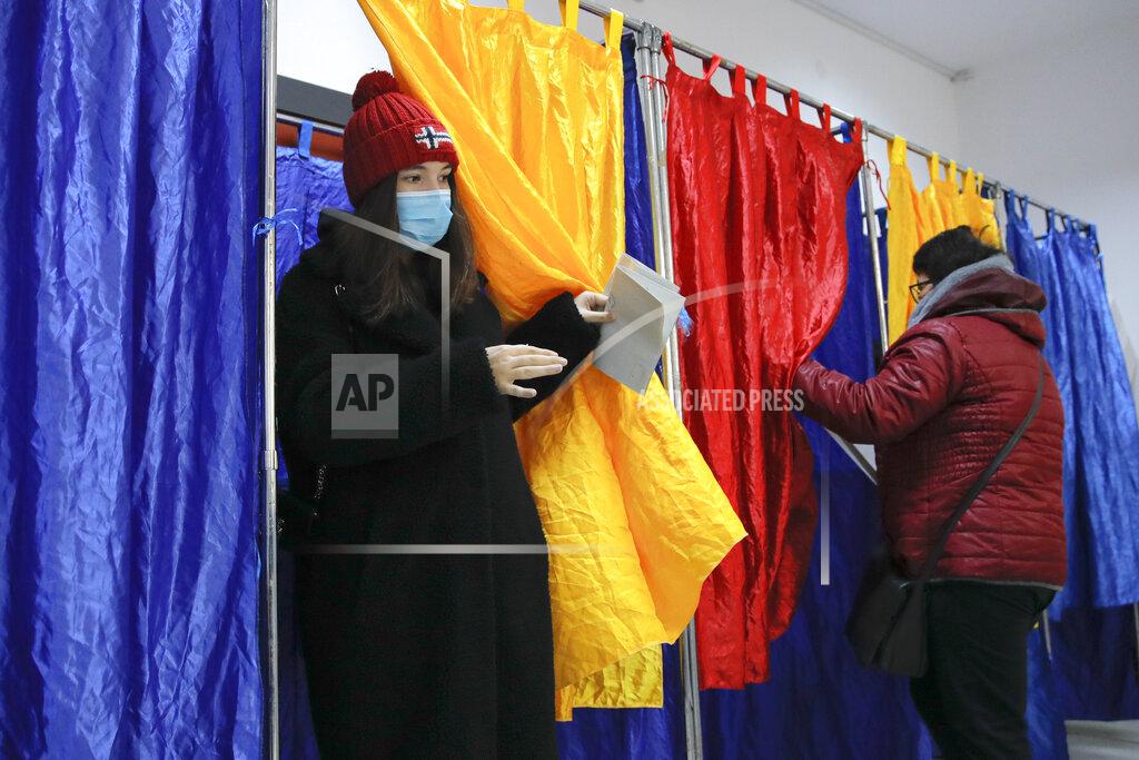 Vadim Ghirda A woman wearing a mask for protection against the COVID-19 infection exits a voting cabin in Bucharest, Romania, Sunday, Dec. 6, 2020. Voting started in Romania's legislative election expected to restore some measure of stability after five years of political and social turbulence with more than 18 million Romanians registered to vote for a new legislative body. (AP Photo/Vadim Ghirda)