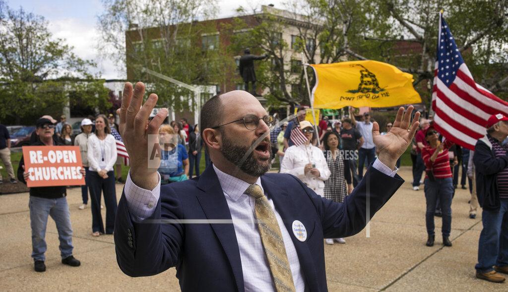 Geoff Forester People gather on the State House grounds with Andrew J. Manuse, chairman of ReOpenNH, center, to celebrate church services along with three local pastors, Saturday, May 16, 2020 in Concord, N.H.. The three pastors spoke from the State House steps, feet away from the signs from the State of New Hampshire saying that more than 10 people was not allowed. The services from noon to 2 p.m. went without any incidents. (Geoff Forester/The Concord Monitor via AP)