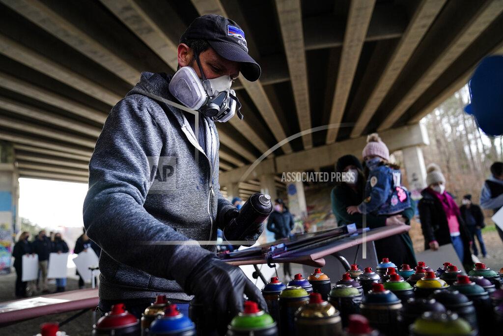 Brynn Anderson Artist Brandon Litman looks for a color to paint a U.S. Senator-elect Jon Ossoff, D-Ga., campaign poster for voters waiting in line after Georgia's Senate runoff race on Sunday, Jan. 10, 2021, in Atlanta. (AP Photo/Brynn Anderson)
