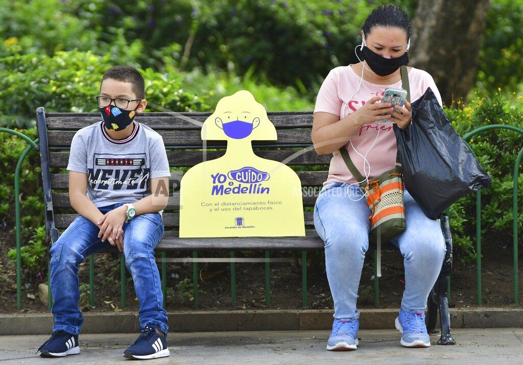 Luis Benavides In this June 8, 2020 photo, a sign reminding citizens to maintain a safe social distance sits on a park bench between a woman and child, amid the new coronavirus pandemic in Medellin, Colombia, which recently went five weeks without a single COVID-19 death. The new challenge for Medellin will be to convince citizens to continue abiding by safety measures like wearing face masks and social distancing. In some poor neighborhoods, local activists say they've encountered skepticism about the virus. (AP Photo/Luis Benavides)