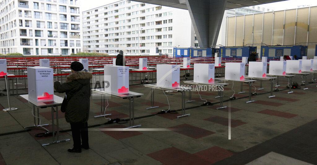 Ronald Zak People wait in front of heating stations to warm the COVID-19 test in a set up for rapid new coronavirus testing in Vienna, Austria, Monday, Nov. 30, 2020. The Austrian government has moved to restrict freedom of movement for people, in an effort to slow the onset of the COVID-19 disease and the spread of the coronavirus. (AP Photo/Ronald Zak)