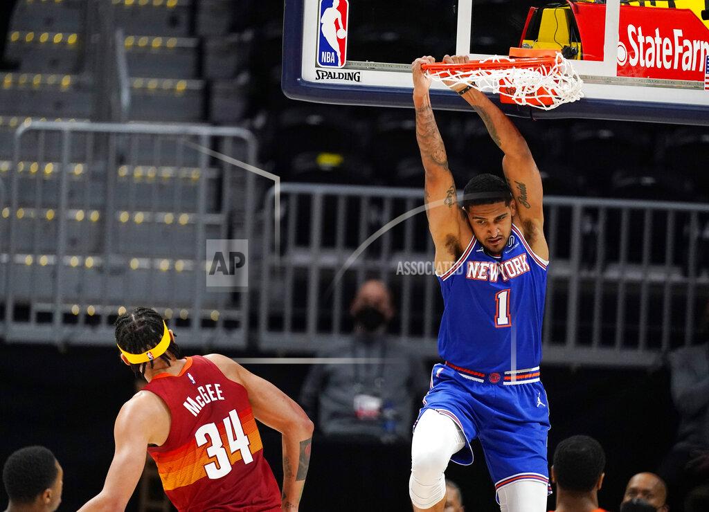 David Zalubowski New York Knicks forward Obi Toppin, right, hangs from the rim after dunking the ball for a basket while Denver Nuggets center JaVale McGee defends in the first half of an NBA basketball game Wednesday, May 5, 2021, in Denver. (AP Photo/David Zalubowski)