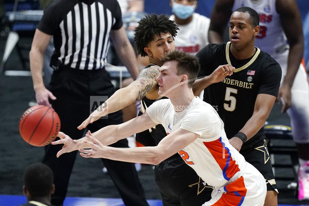 Mark Humphrey Florida's Colin Castleton (12) passes the ball away from Vanderbilt defenders Myles Stute, top left, and D.J. Harvey (5) in the second half of an NCAA college basketball game in the Southeastern Conference Tournament Thursday, March 11, 2021, in Nashville, Tenn. (AP Photo/Mark Humphrey)