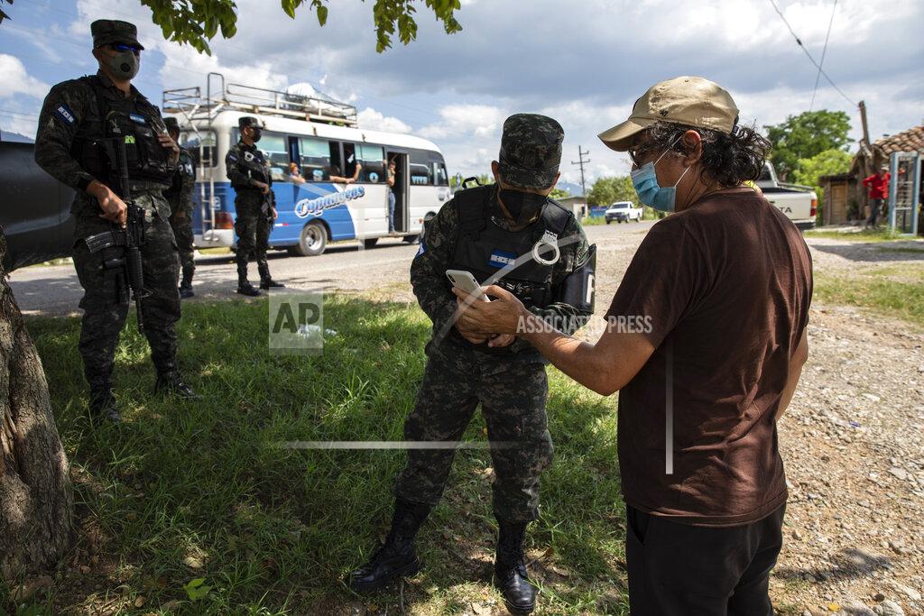 Rodrigo Abd Friar Leopoldo Serrano, right, shows soldiers images he made with his cellphone of a suspicious truck seen near the entrance of his mission, in Mission San Francisco de Asis, Honduras, Friday, June 25, 2021. Serrano’s message is not widely popular. He has sought protection for his mission, which is routinely observed by men passing by in oversized SUVs with tinted windows. (AP Photo/Rodrigo Abd)