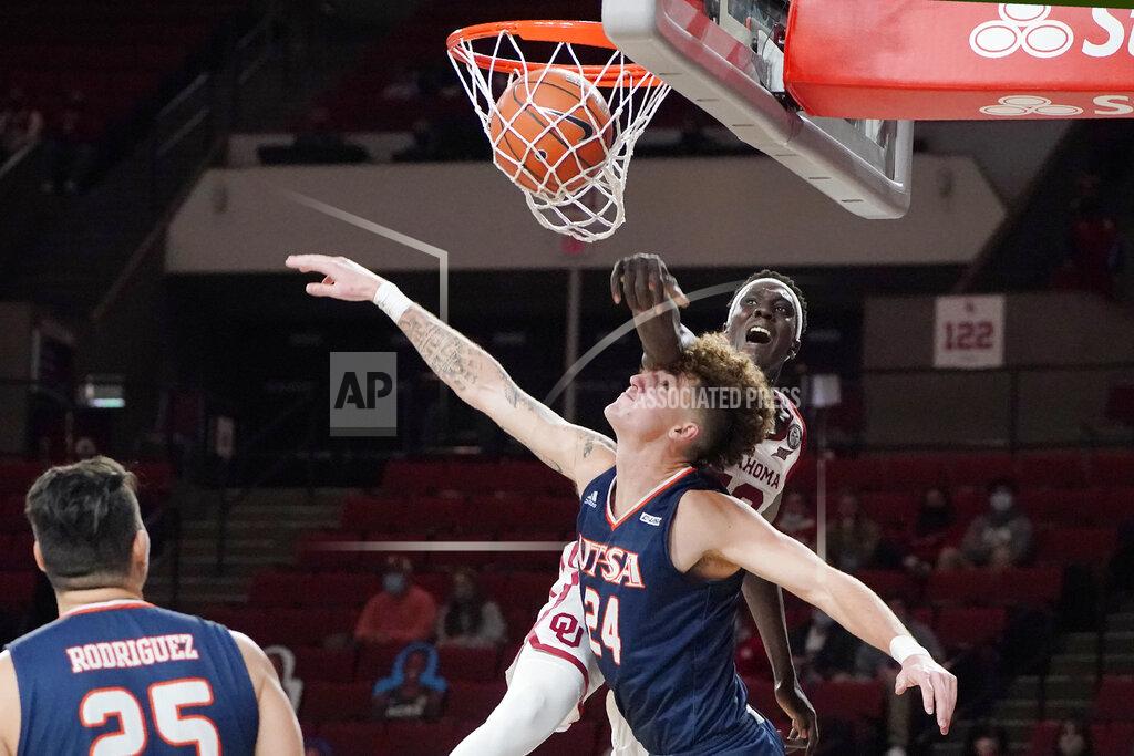 Sue Ogrocki Oklahoma forward Kur Kuath, rear, dunks over UTSA center Jacob Germany (24) during the second half of an NCAA college basketball game Thursday, Dec. 3, 2020, in Norman, Okla. (AP Photo/Sue Ogrocki)