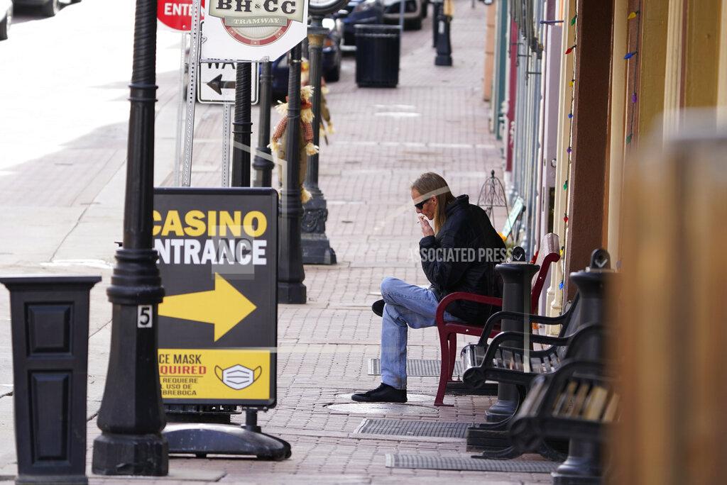 David Zalubowski A lone man sits in front of a casino along Main Street during the coronavirus pandemic Wednesday, Nov. 18, 2020, in the gaming town of Central City, Colo. (AP Photo/David Zalubowski)