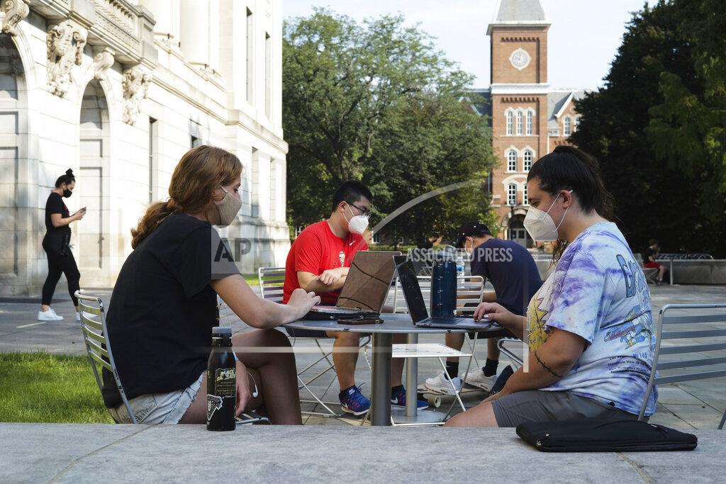 FILE - In this file photo from Aug. 25, 2020, students Jessica DeSena, right, and Camden Coggburn, left, both from Columbus, sit outside Thompson Library during the first day of fall classes at Ohio State University in Columbus, Ohio. Colleges in the U.S. have seen a sharp enrollment drop among international students this fall. University administrators say a number of hurdles and new policies brought on by the coronavirus pandemic are to blame. (Joshua A. Bickel/The Columbus Dispatch via AP, File)