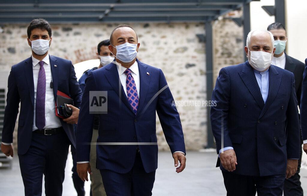 Uncredited Turkish Foreign Minister Mevlut Cavusoglu, center, and Iran's Foreign Minister Mohammad Javad Zarif, right, wearing face masks to protect against the coronavirus, arrive for a meeting, in Istanbul, Monday, June 15, 2020. The two will discuss bilateral issues and Syria. (Turkish Foreign Ministry via AP, Pool)