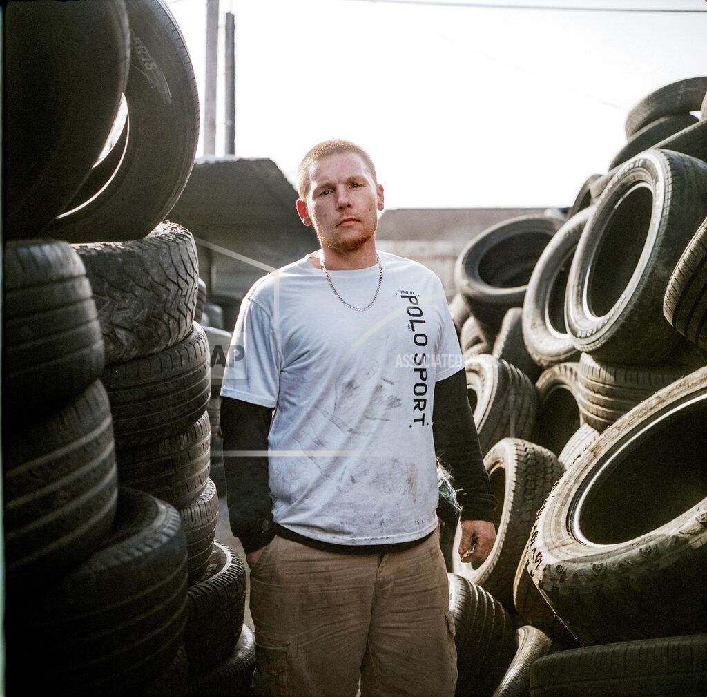 David Goldman In this photo made with a medium format film camera, Steven Ash, 33, stands for a portrait while working at the tire shop his family owns and where he overdosed just days before in Huntington, W.Va., Wednesday, March 17, 2021. Ash was 19 when he took his first OxyContin pill and his life unraveled after that, cycling through jails, he said. The last year has been particularly brutal. His cousin died from an overdose in somebody's backyard. He has a friend in the hospital in her 20s scheduled for open-heart surgery from shooting drugs with dirty needles, and the doctors aren't sure she'll make it. He had three agonizing surgeries himself from drug-related infections. He took more drugs to numb the pain, but it made things worse, a vicious cycle, he said. He knows he's putting his mother through hell. "I fight with myself every day. It's like I've got two devils on one shoulder and an angel on the other," he said. "Who is going to win today?" (AP Photo/David Goldman)
