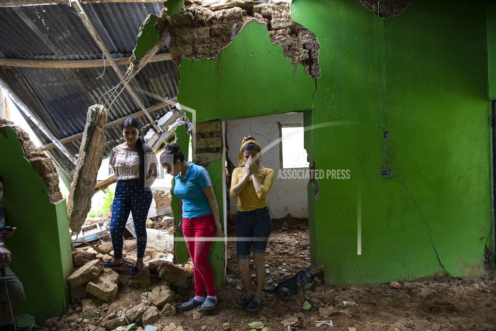 Rodrigo Abd Marian Castron, from left, Maria Castron, 25, and Jenny Castron, 19, visit their home devastated by a landslide triggered by consecutive hurricanes in La Reina, Honduras, Friday, June 25, 2021. The Honduran town was hammered in November 2020 by Hurricanes Eta and Iota and then obliterated by a mudslide. (AP Photo/Rodrigo Abd)