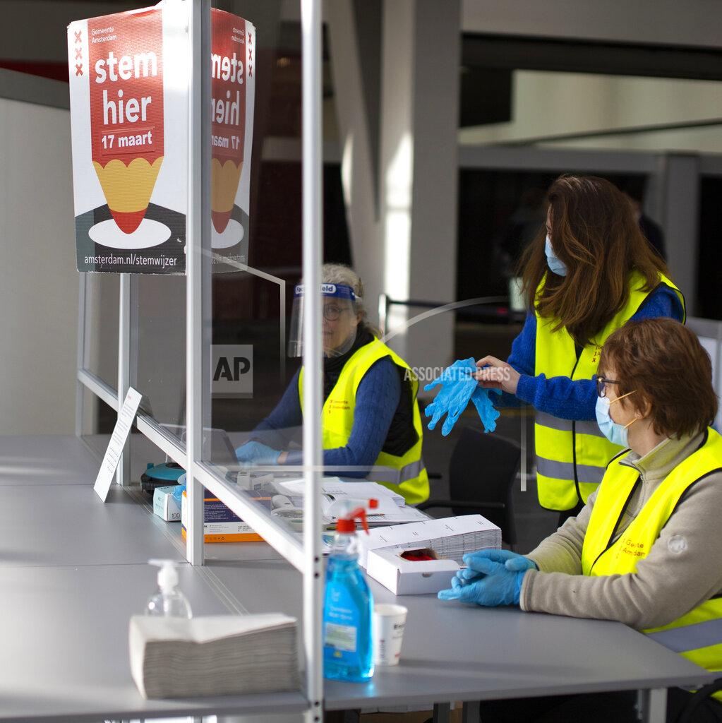 Peter Dejong Elections officials take COVID-19 related sanitary precautions in a ride through polling station for bicycles in Amsterdam, Netherlands, Monday, March 15, 2021. Polling stations opened across the Netherlands early Monday in a general election that has been spread over three days to allow people to vote safely during the coronavirus pandemic. (AP Photo/Peter Dejong)