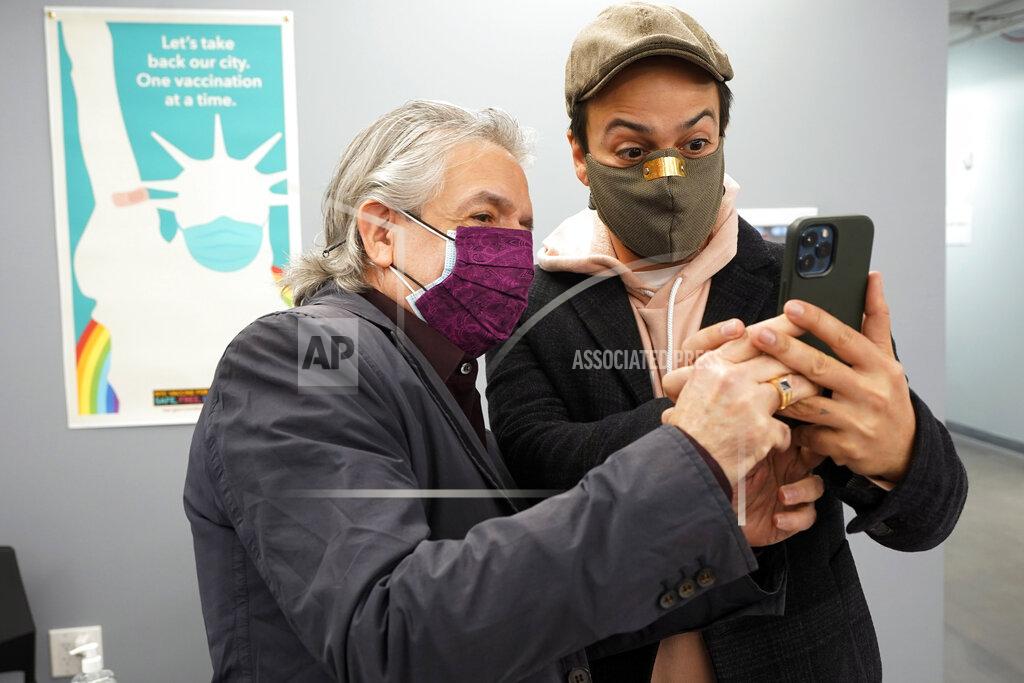 Richard Drew Actor Lin-Manuel Miranda, right, and his father, Luis A. Miranda, Jr., look at a mobile phone before they tour the grand opening of a Broadway COVID-19 vaccination site intended to jump-start the city's entertainment industry, in New York, Monday, April 12, 2021. (AP Photo/Richard Drew, Pool)