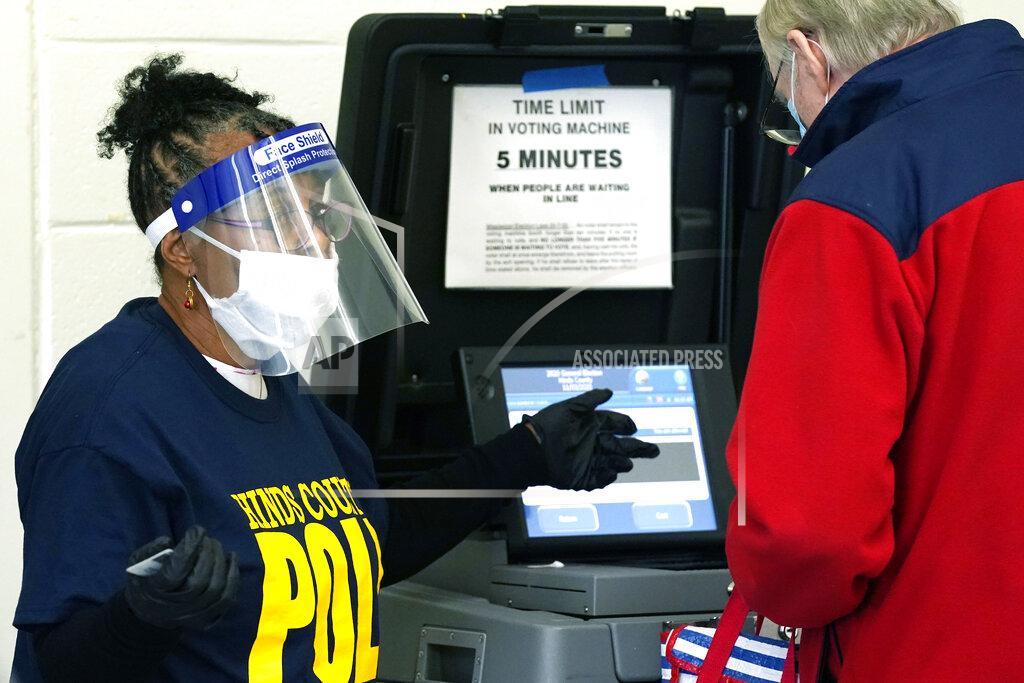Rogelio V. Solis FILE - In this Nov. 3, 2020, file photo, Precinct 36 poll worker Vivian Bibens wears personal protective equipment as she explains the purpose of the ballot scanner to a voter on Election Day in Jackson, Miss. The 2020 presidential election had all the makings of a looming disaster: fears of Russian meddling, violence at the polls, voter intimidation and poll workers fleeing their posts over the coronavirus. But the election was largely smooth, in large part because 107 million voters that cast their ballots early and took the pressure off Election Day operations. (AP Photo/Rogelio V. Solis, File)