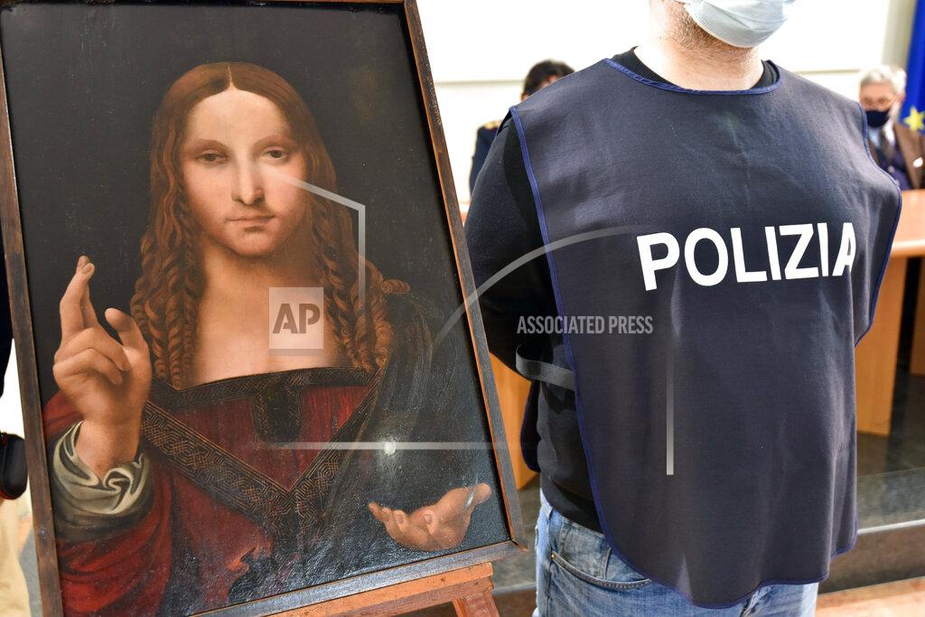 Polizia Di Stato An Italian police officer stands by a copy of the “Salvator Mundi” (Savior of the World) by Leonardo da Vinci, in Naples, Italy, Wednesday, Jan. 20, 2021. Italian police have recovered a copy of Leonardo da Vinci’s 16th century “Salvator Mundi” painting of Jesus Christ that was stolen from a Naples church without the priests even realizing it was gone. The discovery was made over the weekend when Naples police working on a bigger operation found the painting hidden in an apartment. Police chief Alfredo Fabbrocini said the owner offered a “less than credible” explanation that he had “casually” bought it at a small market. (Italian Police via AP)