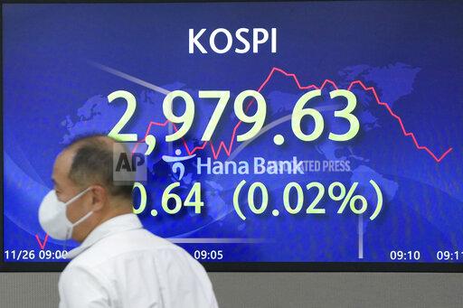 A currency trader walks by the screens showing the Korea Composite Stock Price Index (KOSPI) at a foreign exchange dealing room in Seoul, South Korea, Friday, Nov. 26, 2021. Asian stock markets sank Friday as traders watched a surge in coronavirus cases in Europe and anti-disease controls that threaten to disrupt trade and travel.(AP Photo/Lee Jin-man)