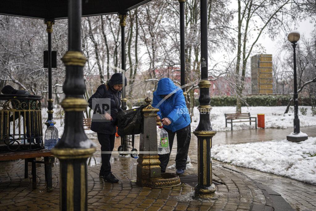 Evgeniy Maloletka People collect water, in Kyiv, Ukraine, Thursday, Nov. 24, 2022. Residents of Ukraine's bombed but undaunted capital clutched empty bottles in search of water and crowded into cafés for power and warmth Thursday, switching defiantly into survival mode after new Russian missile strikes a day earlier plunged the city and much of the country into the dark. (AP Photo/Evgeniy Maloletka)