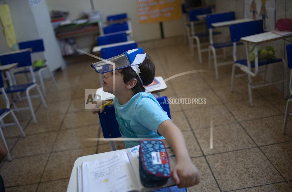 Silvia Izquierdo Bernardo Santo attends a class wearing a face shield, at the Pereira Agustinho daycare, nursery school and pre-school, after it reopened amid the new coronavirus pandemic in Duque de Caxias, Monday, July 6, 2020. The city of Manaus in the Amazon rainforest and Duque de Caxias in Rio de Janeiro’s metropolitan region, became on Monday the first Brazilian cities to resume in-person classes at private schools since the onset of the COVID-19 pandemic, according to the nation's private school federation. (AP Photo/Silvia Izquierdo)