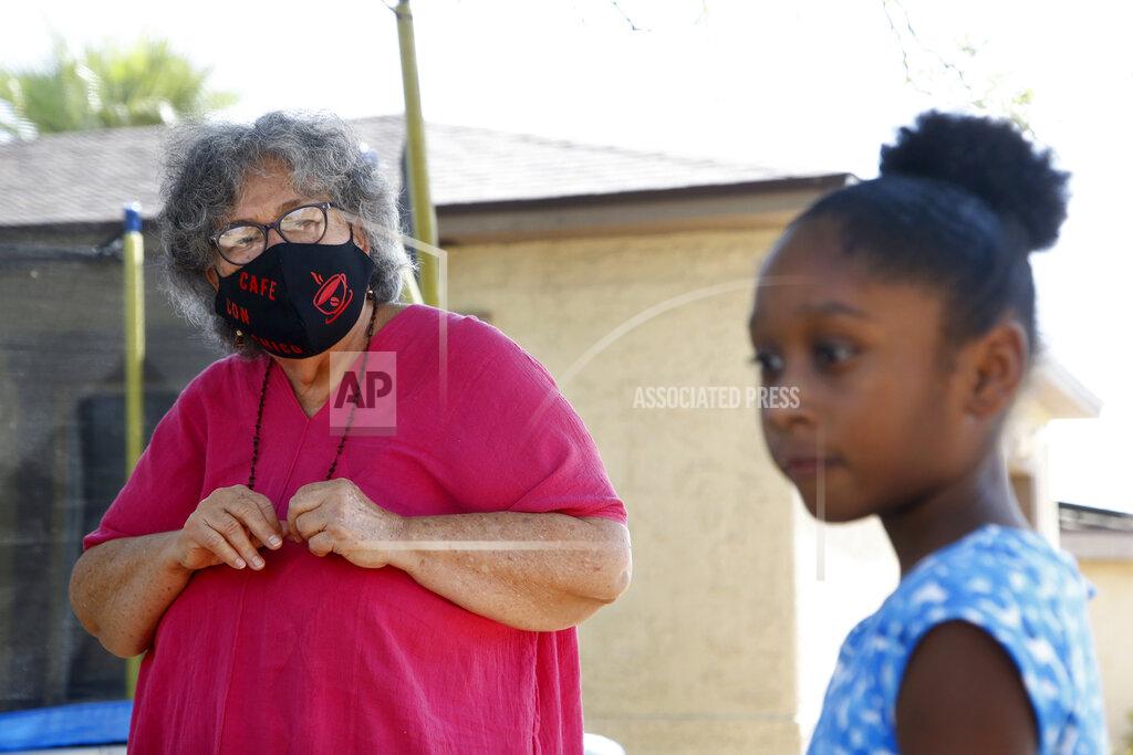 Ross D. Franklin Zita Robinson, left, who's 77 and diabetic, looks at her granddaughter, 8-year-old Traris "Trary" Robinson-Newman, from a safe distance Tuesday, Aug. 4, 2020, in Phoenix. Robinson has been careful around her granddaughter amid the coronavirus pandemic. (AP Photo/Ross D. Franklin)