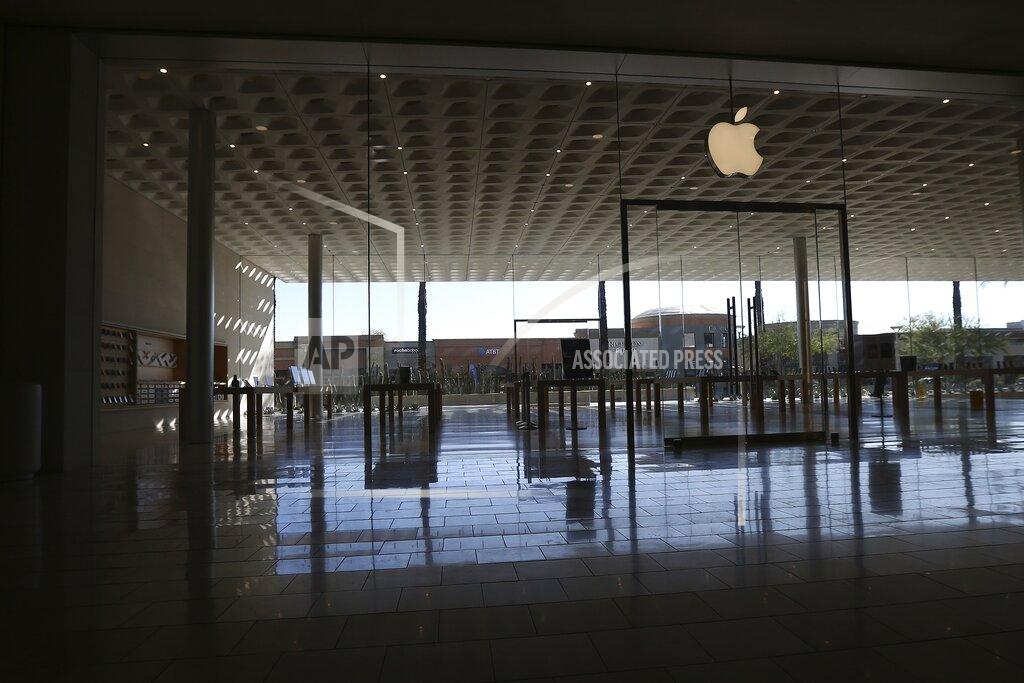 FILE - In this March 14, 2020 file photo, an Apple retail store is closed at a local mall in Scottsdale, Ariz. Apple is temporarily closing 11 stores in Arizona, Florida, North Carolina and South Carolina just few weeks after reopening them in hopes that consumers would be able to shop in them without raising the risk of infecting them or company workers with the novel coronavirus that caused COVID-19. (AP Photo/Ross D. Franklin, File)