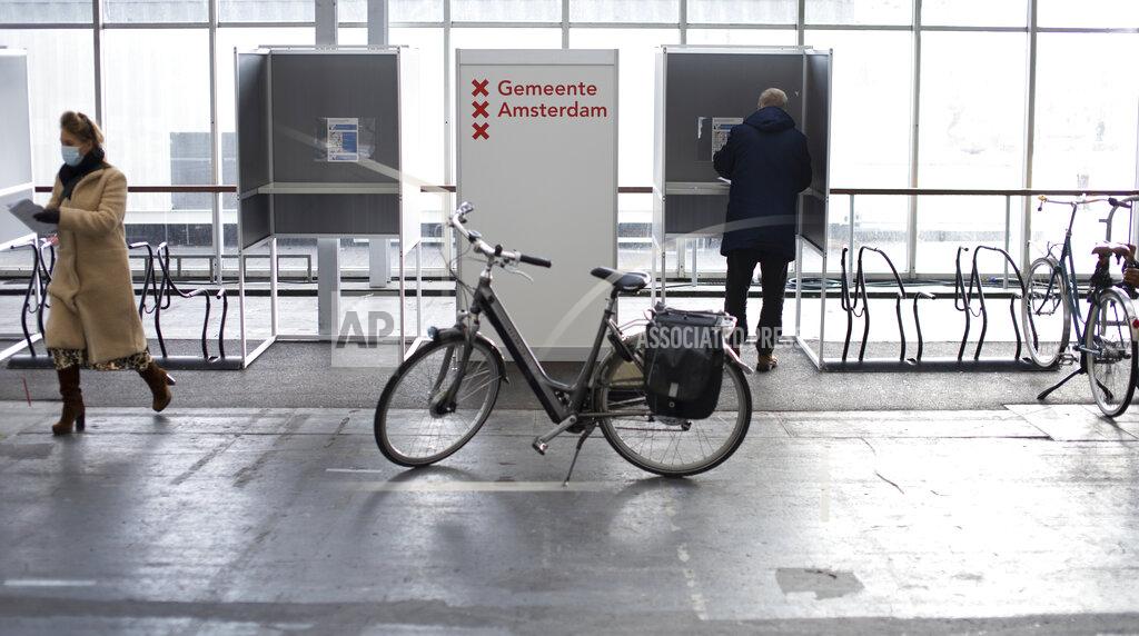 Peter Dejong People cast their ballots in a ride through polling station for bicycles in Amsterdam, Netherlands, Monday, March 15, 2021. Polling stations opened across the Netherlands early Monday in a general election that has been spread over three days to allow people to vote safely during the coronavirus pandemic. (AP Photo/Peter Dejong)