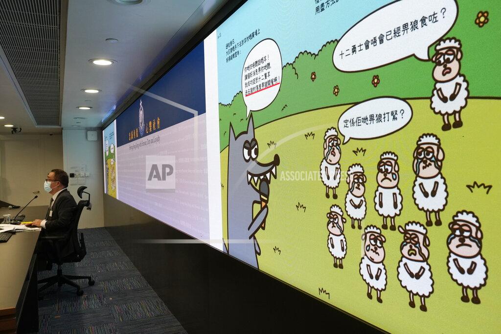Vincent Yu Li Kwai-wah, left, senior superintendent of Police National Security Department speaks in front of a screen showing evidence including the contents of three children's books on stories that revolve around a village of sheep which has to deal with wolves from a different village, before a press conference in Hong Kong Thursday, July 22, 2021. Hong Kong's national security police on Thursday arrested five people from a trade union of the General Association of Hong Kong Speech Therapists on suspicion of conspiring to publish and distribute seditious material, in the latest arrests made amid a crackdown on dissent in the city. (AP Photo/Vincent Yu)