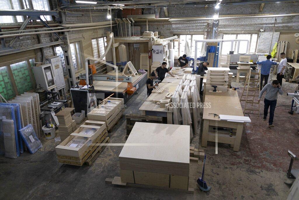Alexander Zemlianichenko Employees of Stend-Do, a business that built stands for exhibitions, work in Moscow, Russia, Friday, March 26, 2021. When the convention business ground to a halt during the pandemic, Artyom Borovoy's company switched to making folding desks for those working from home — an idea he said came from Zoom discussions with his friends “out of desperation.” Simple plywood desks that fold like an easel and can be used either sitting or standing proved popular for those working remotely from tiny apartments. (AP Photo/Alexander Zemlianichenko)