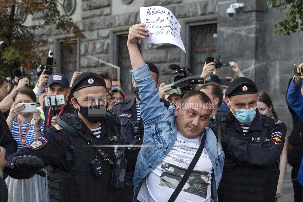 Pavel Golovkin Police officers detain a protester as he comes to support Russian opposition leader Alexei Navalny in front of the building of the Federal Security Service (FSB, Soviet KGB successor) in Moscow, Russia, Thursday, Aug. 20, 2020. The banner reads: "Navalny live!!! Politkovskaya? Nemtsov? Who is next? Putin is a thief" Russian opposition politician Alexei Navalny is on a hospital ventilator in a coma, after falling ill from a suspected poisoning, according to his spokeswoman Kira Yarmysh. (AP Photo/Pavel Golovkin)