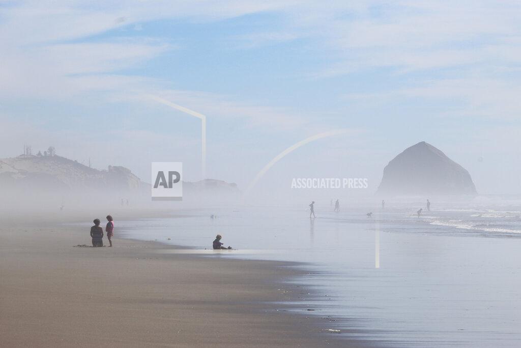 Andrew Selsky FILE - People walk on the beach at Tierra del Mar, Ore., on, Aug. 17, 2020. The Oregon Coast is featured in a collection of mini-essays by American writers published online by the Frommer's guidebook company about places they believe helped shape and define America. (AP Photo/Andrew Selsky, File)