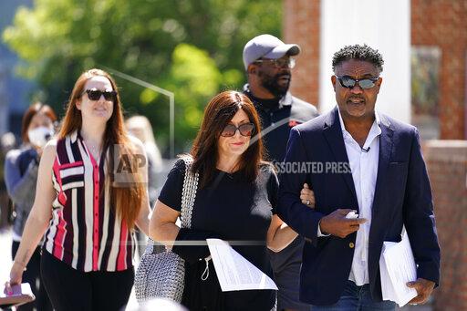 FILE - In this May 14, 2021, file photo, former NFL players Ken Jenkins, right, and Clarence Vaughn III, center right, along with their wives, Amy Lewis, center, and Brooke Vaughn, left, carry petitions demanding equal treatment for everyone involved in the settlement of concussion claims against the NFL, to the federal courthouse in Philadelphia, in this Friday, May 14, 2021, file photo. Lawyers for the NFL and retired players filed proposed changes to the $1 billion concussion settlement on Wednesday, Oct. 20, 2021, to remove race-norming in dementia testing, which made it more difficult for Black players to qualify for payments. (AP Photo/Matt Rourke, File)