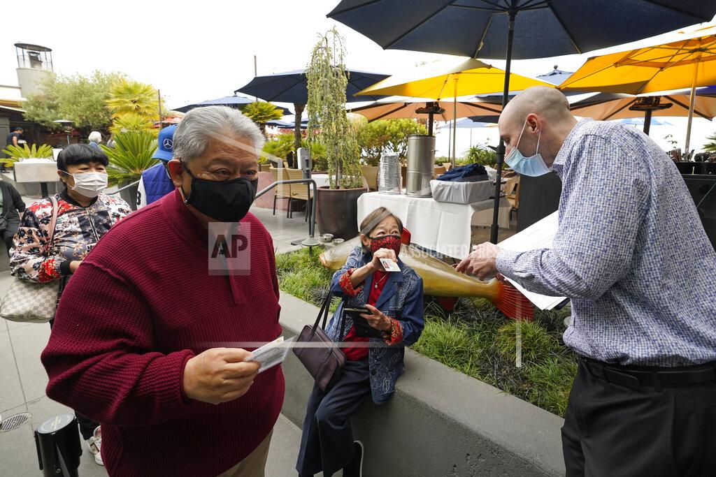 Eric Risberg FILE - In this Aug. 20, 2021, file photo, host Jason Pryor, right, checks the vaccination and identification cards of diners as they enter the Waterbar restaurant in San Francisco. Ticket agents dutifully ascertain the vaccination status of everyone passing through the turnstile at pro sports venues in some cities from Seattle and New York, and restaurant hosts do the same in many places. (AP Photo/Eric Risberg, File)